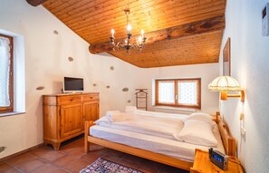 Ein Schlafzimmer mit einem Holzbett, einem Fernseher auf einer Holzkommode, einer Kristallleuchtre und einer Nachttischlampe.