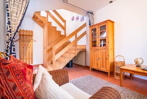 Ein gemütliches Zimmer mit einer Holztreppe, einem Korbsessel, einem Holzschrank und einem kleinen Tisch mit Globus.