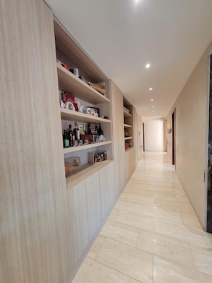 A hallway with built-in shelving on one side, a tiled floor, and recessed ceiling lighting. - Luxury Lakeview Penthouse (Montagnola)