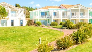 A multi-story hotel with balconies, a grassy lawn, and a pathway. - Coastal 2-room Apartment for 5 Guests in Chateau-d'olonne (Les Sables-d'Olonne)