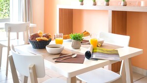 A breakfast table with bread, juice, and a newspaper. - Coastal 2-room Apartment for 5 Guests in Chateau-d'olonne (Les Sables-d'Olonne)