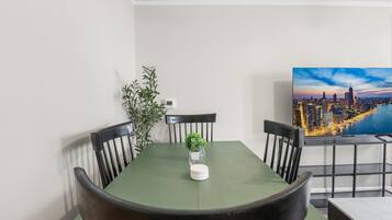 A dining area with a table, chairs, a potted plant, and a cityscape view.