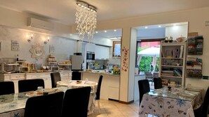 Una cocina amplia con electrodomésticos modernos, un comedor con candelabro y una estantería llena de libros y objetos decorativos.