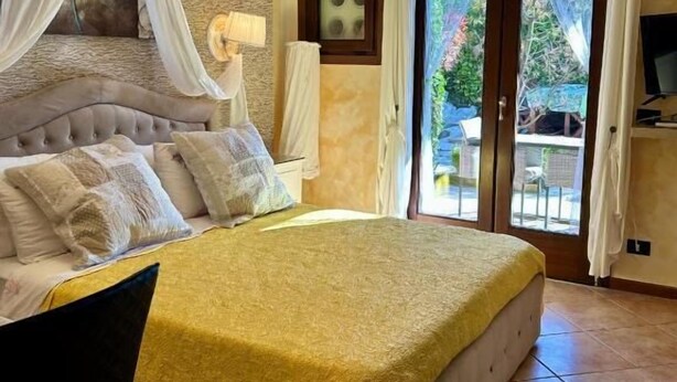 Un dormitorio con una cama grande, una araña, un televisor y vistas al exterior.