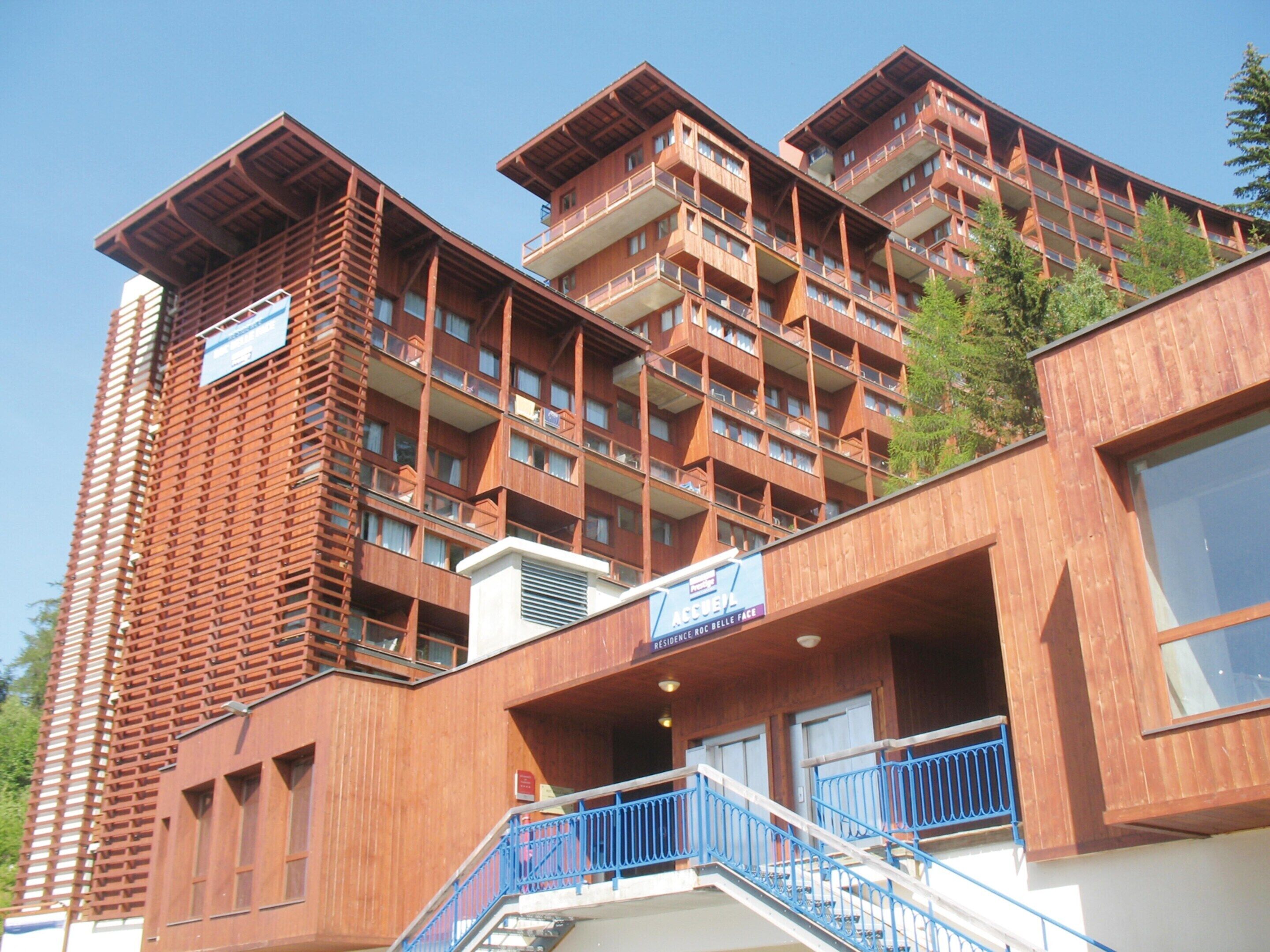 Un hotel de varios pisos con un diseño arquitectónico moderno, que cuenta con balcones y una escalera.