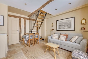 A living room with a staircase, a sofa, a table, and a framed picture on the wall. - A Sophisticated 1-BR - Saint-Germain (Paris)