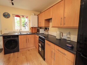 A kitchen with wooden cabinets, a dishwasher, a stove, a microwave, and a kettle. - Mellbeck Retreat (Kirkby Stephen)