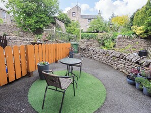 A patio with a round table and two chairs, surrounded by a stone wall and a wooden fence. - Mellbeck Retreat (Kirkby Stephen)