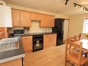 Una cocina moderna con armarios de madera, un refrigerador negro, un microondas y un lavavajillas.