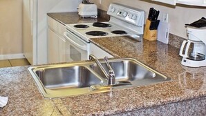 Una cocina con estufa, pileta, tostadora y cafetera.