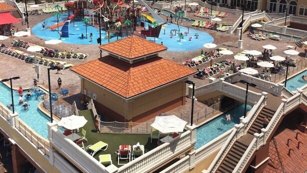 Un hotel con varias piscinas, parque acuático y un edificio grande con balcones.