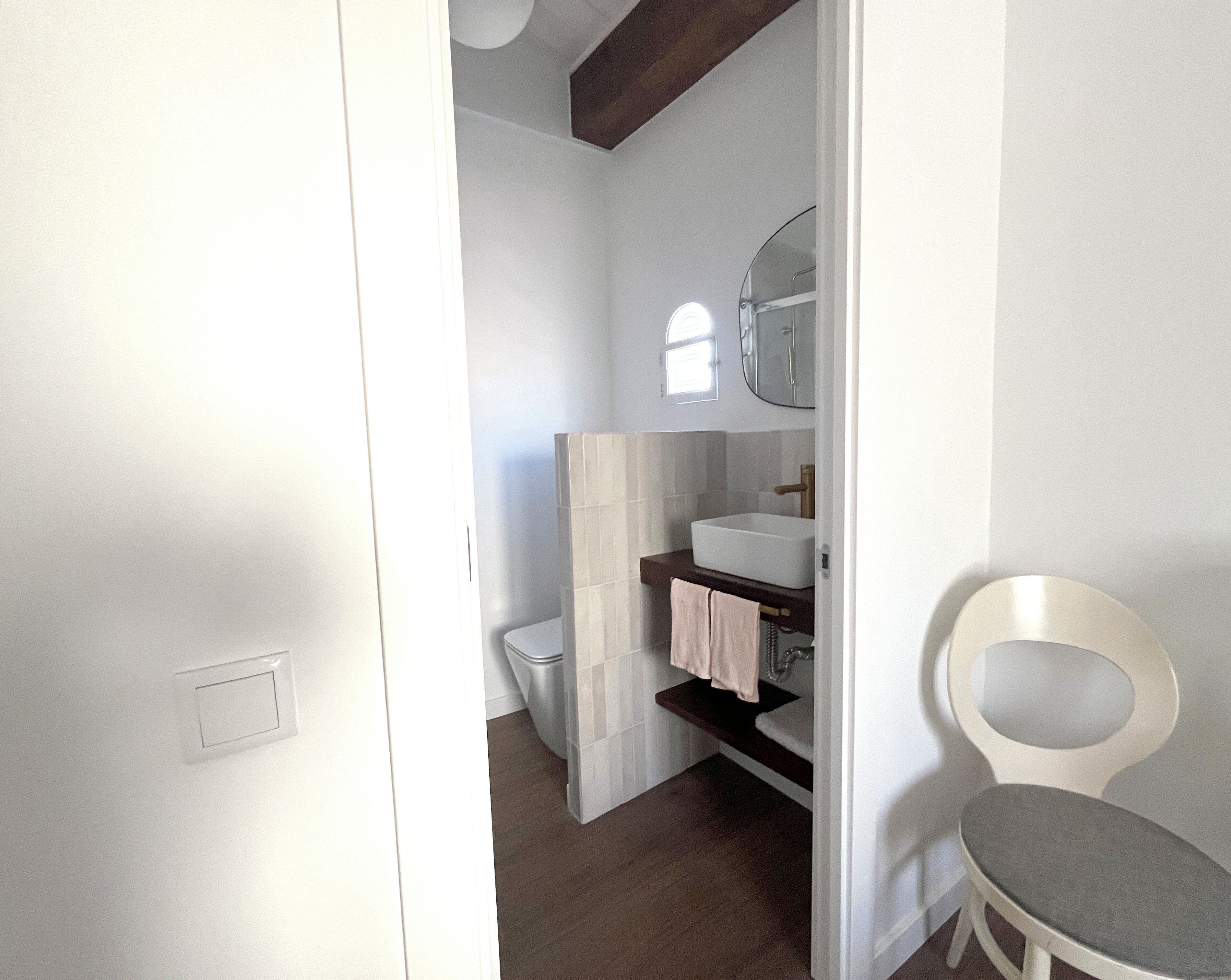 A bathroom with a toilet, sink, mirror, and towel rack.