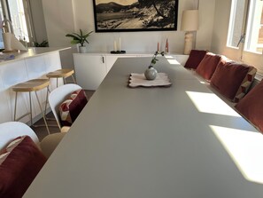 A modern dining room with a long table, chairs, a vase, and a framed picture on the wall. - Can Clavetaires (Campdevànol)