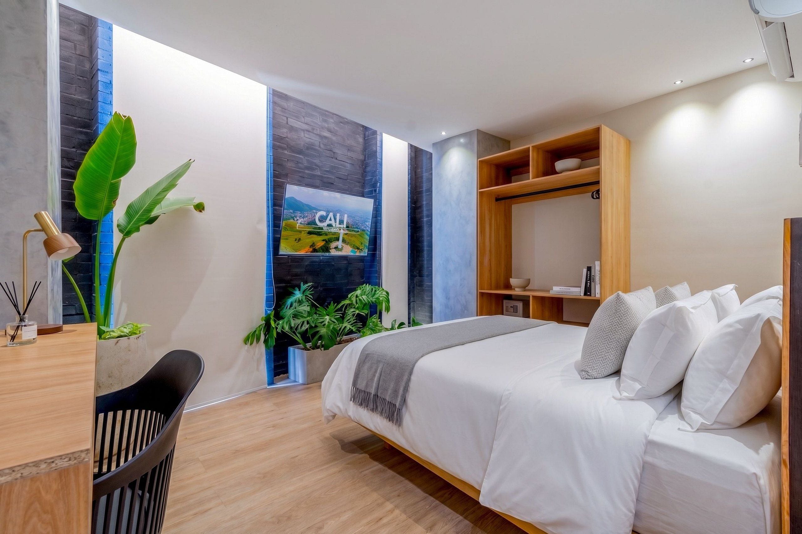 A modern bedroom with a bed, a desk, and a view of a cityscape.