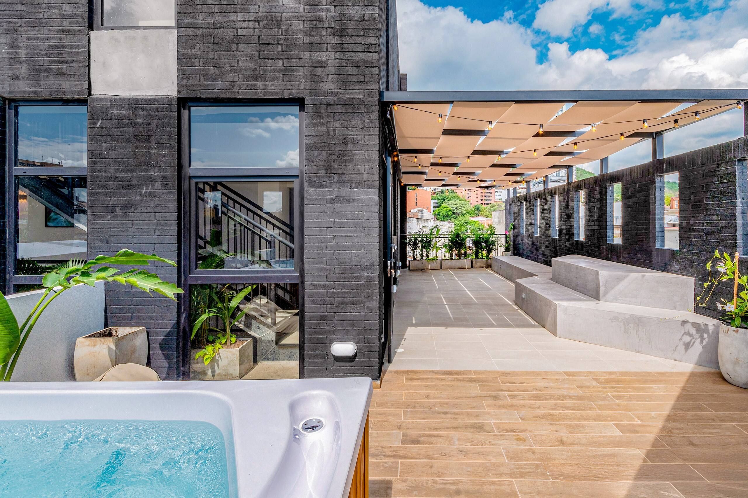 Un edificio moderno con una zona de piscina, asientos al aire libre y una escalera que conduce a un nivel superior.