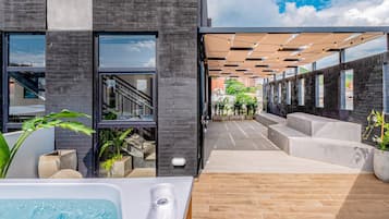 Un edificio moderno con una zona de piscina, asientos al aire libre y una escalera que conduce a un nivel superior.