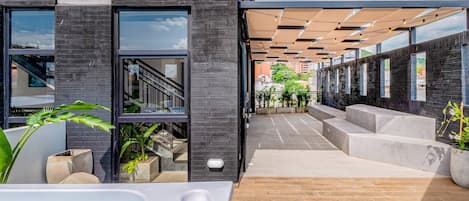 A modern building with a pool area, outdoor seating, and a staircase leading to an upper level.