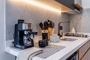A modern kitchen with a built-in coffee maker, a sink, and a stove.