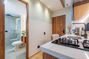 Un baño moderno con cabina de ducha de vidrio, inodoro y lavamanos con estufa.