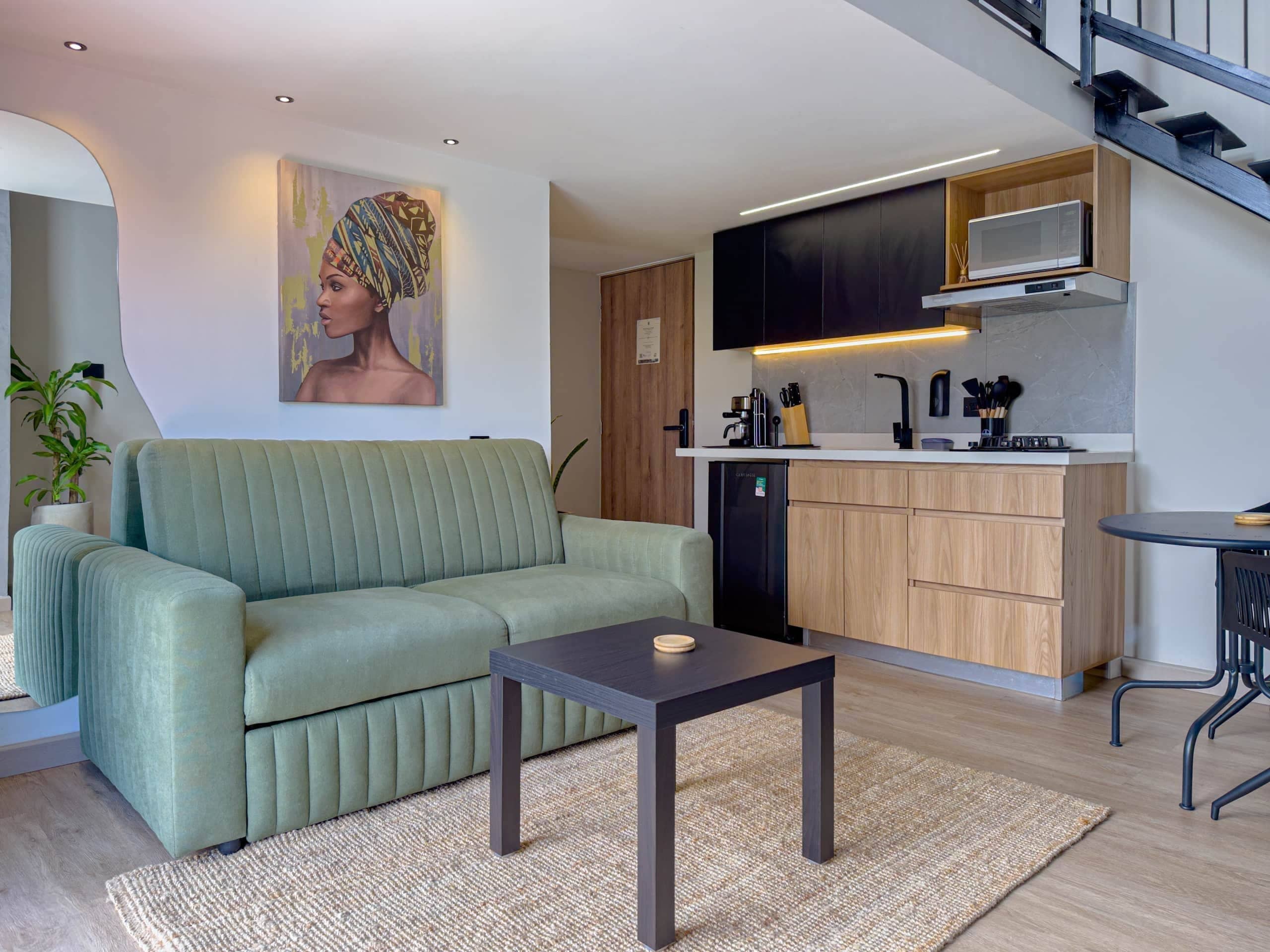 Un espacio moderno para vivir con sofá, una mesa de centro, una cocina con microondas y una escalera.