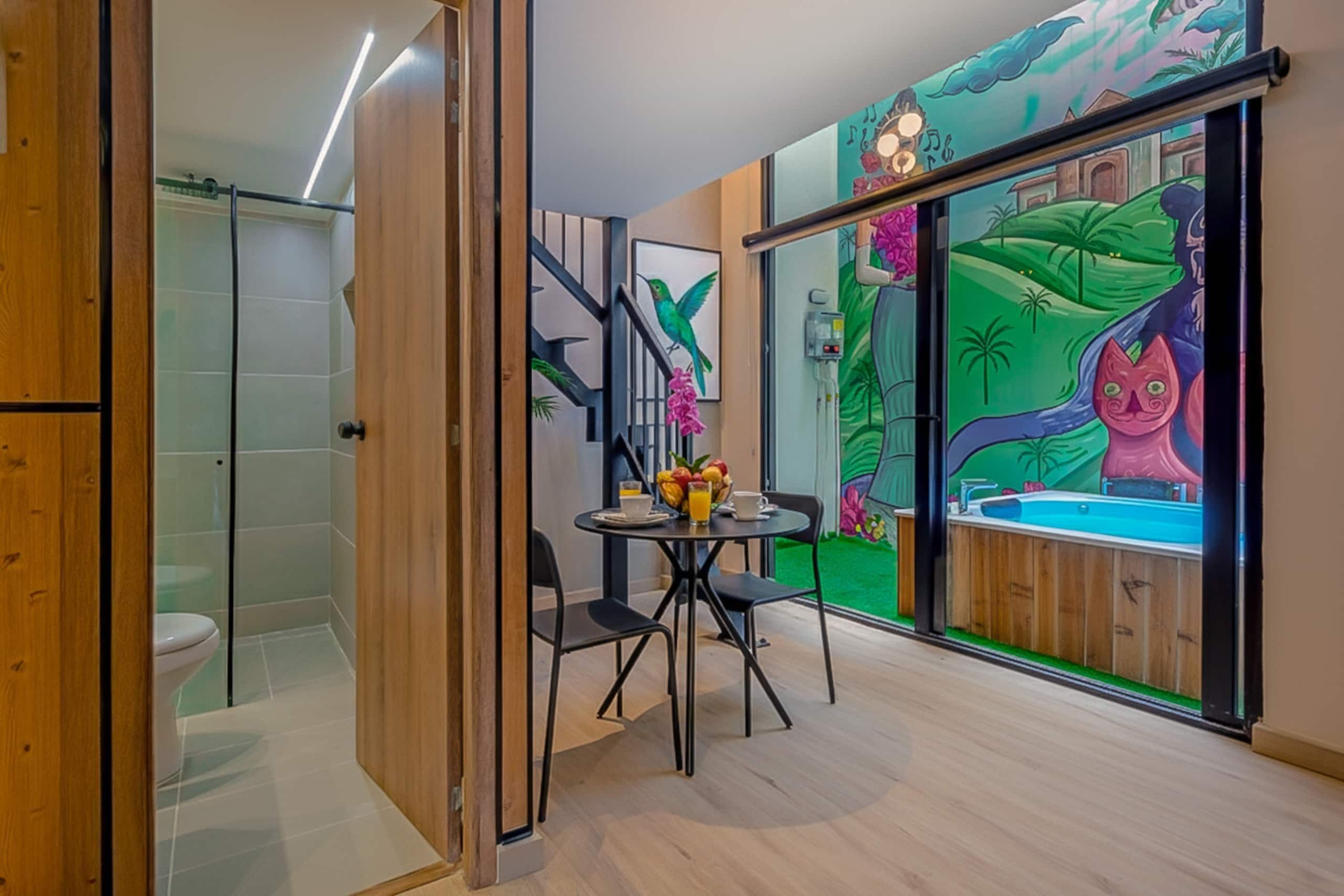 Une salle de bain moderne équipée d’une douche, de toilettes et d’une porte en verre donnant sur un coin repas avec une table et des chaises.