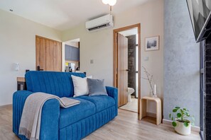 A modern living room with a blue sofa, a small side table with a plant, and a fireplace.