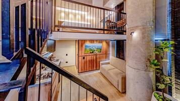 Un intérieur à plusieurs niveaux comprenant un escalier, un canapé, un téléviseur et une plante.