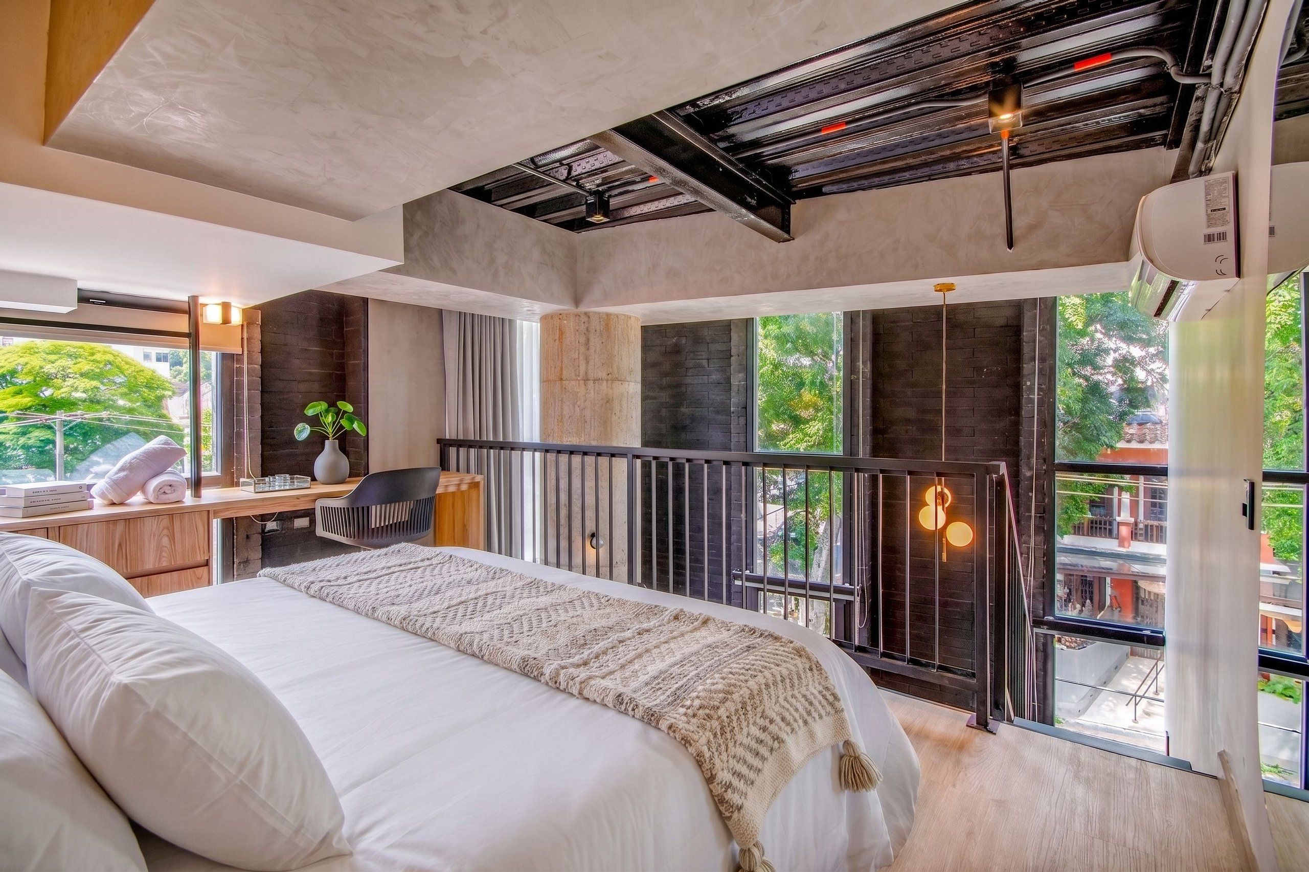 Un dormitorio moderno con una cama grande, un escritorio y un balcón con vistas.
