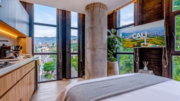 Une chambre d’hôtel moderne dotée d’un grand lit, d’un coin cuisine et d’un téléviseur offrant une vue sur Cali, en Colombie.