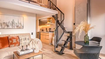 Una sala de estar moderna con un sofá, una mesa de centro y una escalera que conduce a un nivel superior.