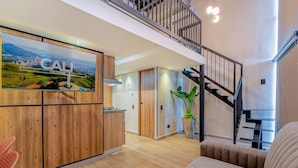 A modern interior with a wooden kitchen, a staircase, and a living area with a sofa.