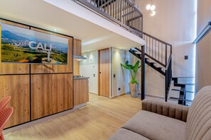 A modern interior with a wooden kitchen, a staircase, and a living area with a sofa.