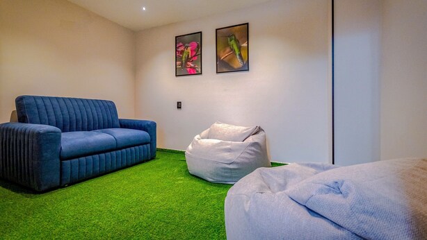 A room with a blue sofa, a white bean bag, and a green carpet. - Edificio Constantino Living Cali (Cali)