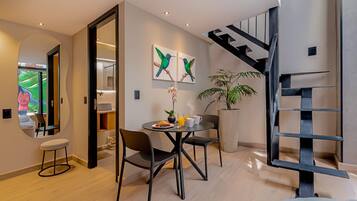 Un interior moderno con zona de comedor, escalera y un espejo grande.