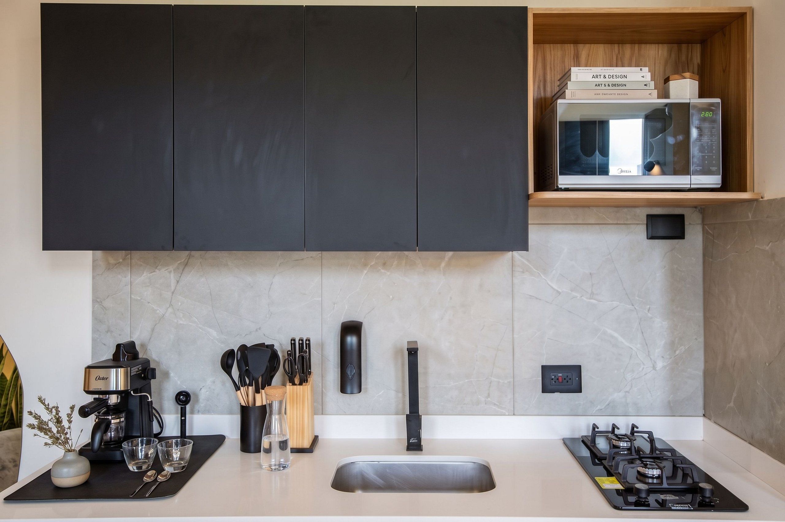 A modern kitchen with black cabinets, a built-in microwave, a gas stove, and a coffee maker.