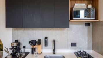 A modern kitchen with black cabinets, a built-in microwave, a gas stove, and a coffee maker.