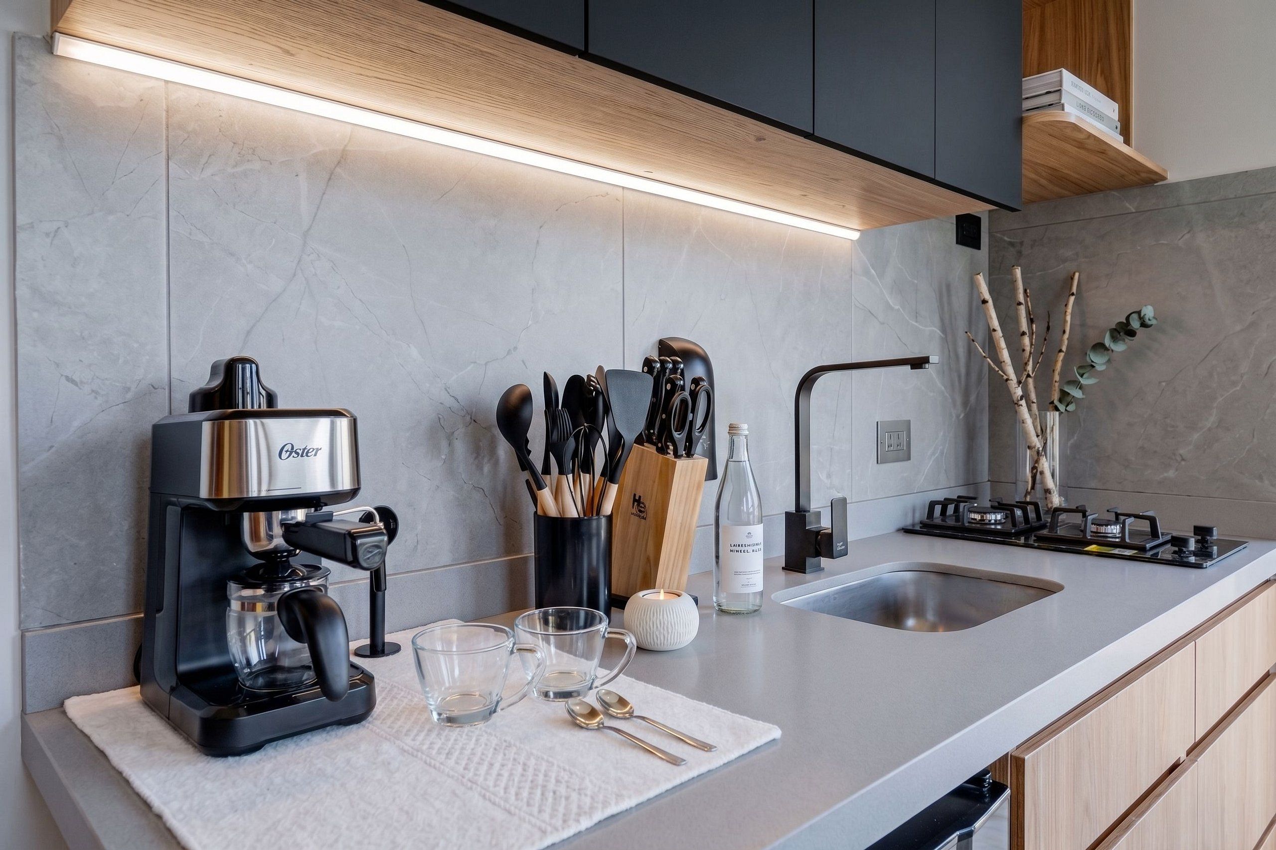 A modern kitchen with a built-in coffee maker, a gas stove, and a knife block.