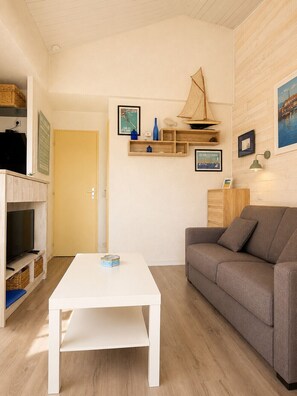A room with a white table, a gray sofa, wooden shelves with decorative items, and a door.