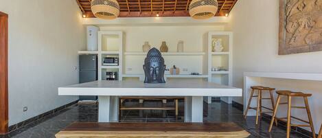 A modern kitchen with a central island, wooden stools, and a ceiling fan.