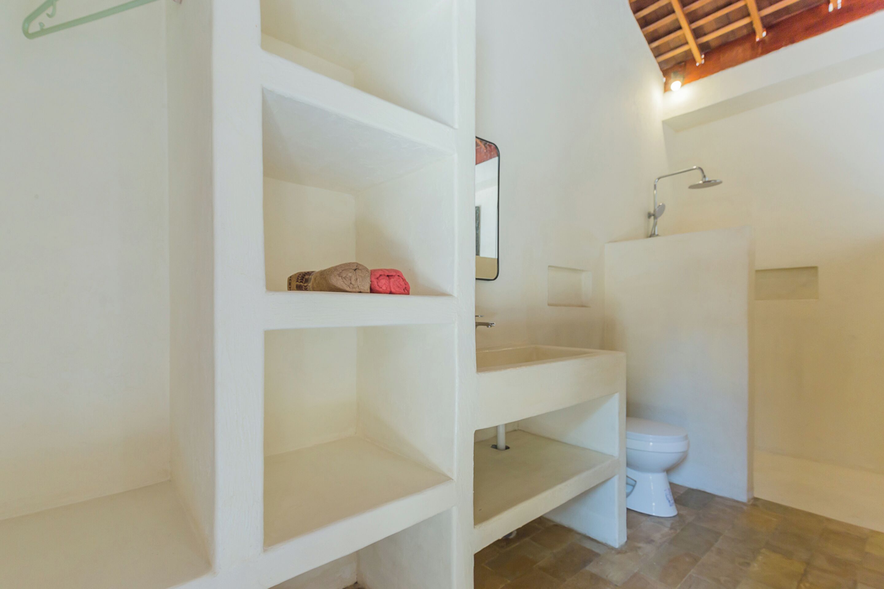 A bathroom with a toilet, a sink, a shower, and a mirror.