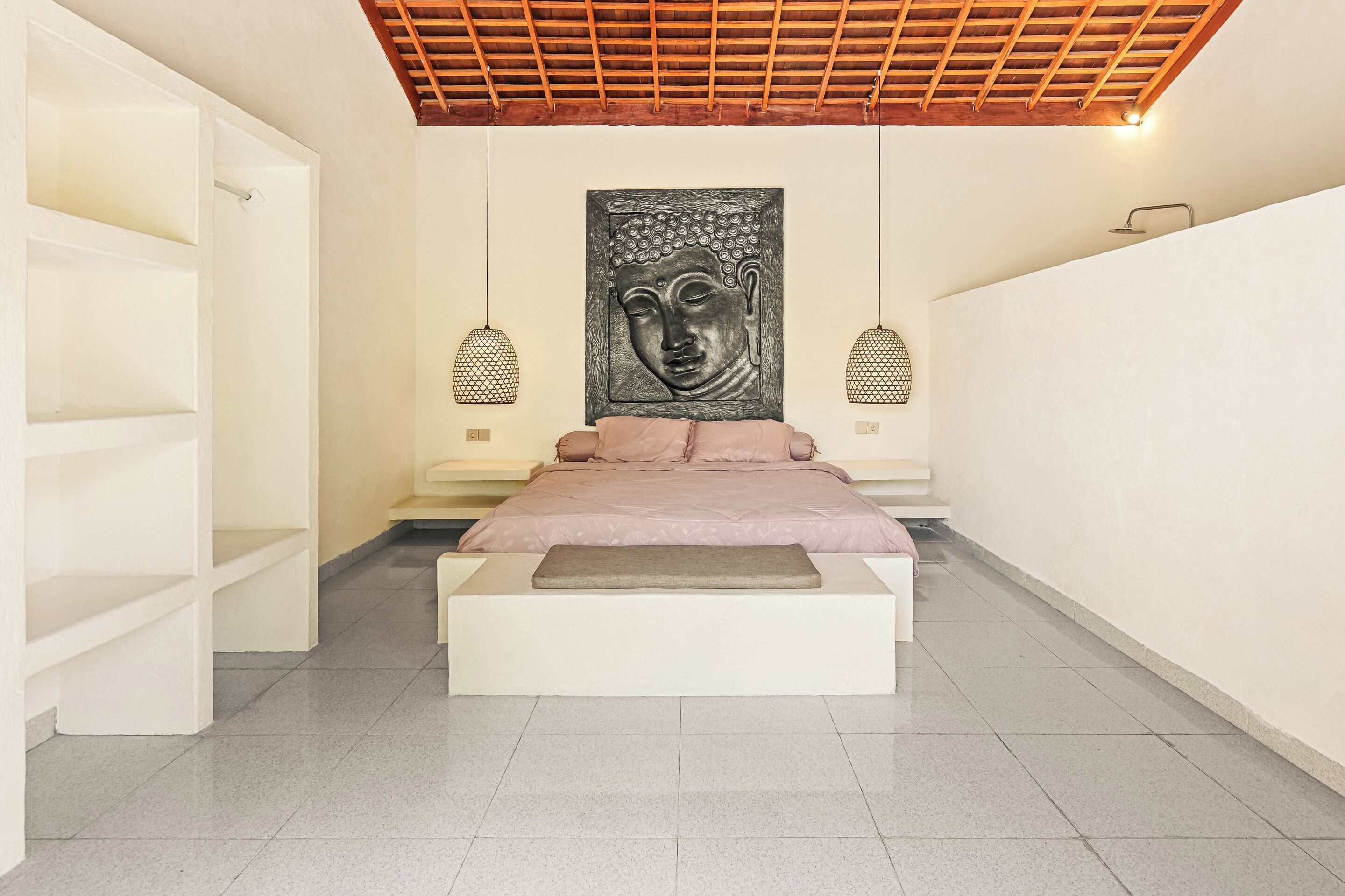 A modern bedroom with a bed, a large wall-mounted Buddha sculpture, and two pendant lights.