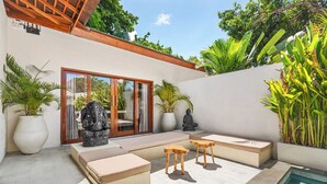 A modern outdoor patio with seating, a pool, and tropical plants. - Tropical Villas Jimbaran (Jimbaran)