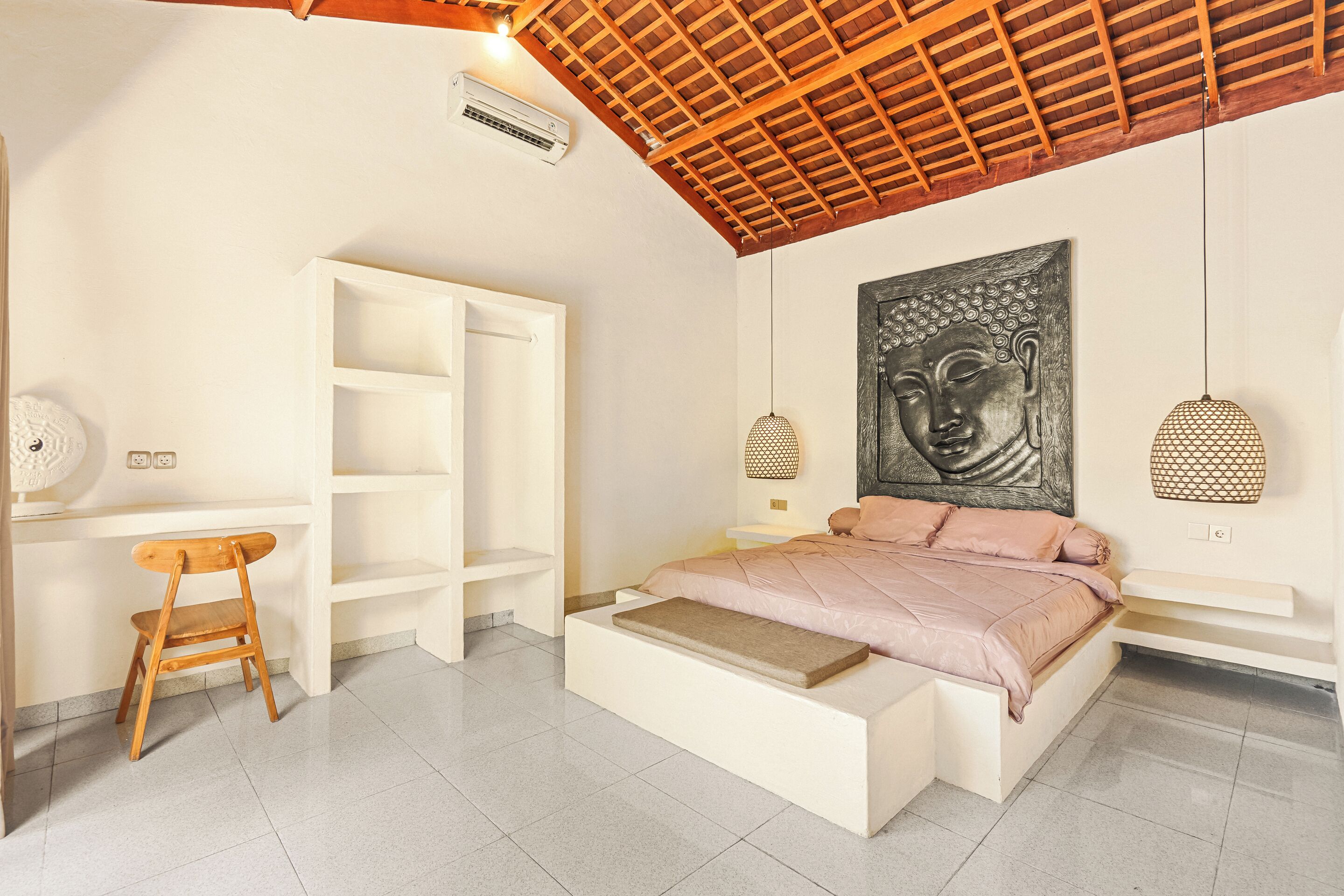 A bedroom with a bed, a wooden chair, a white wardrobe, and a Buddha painting.