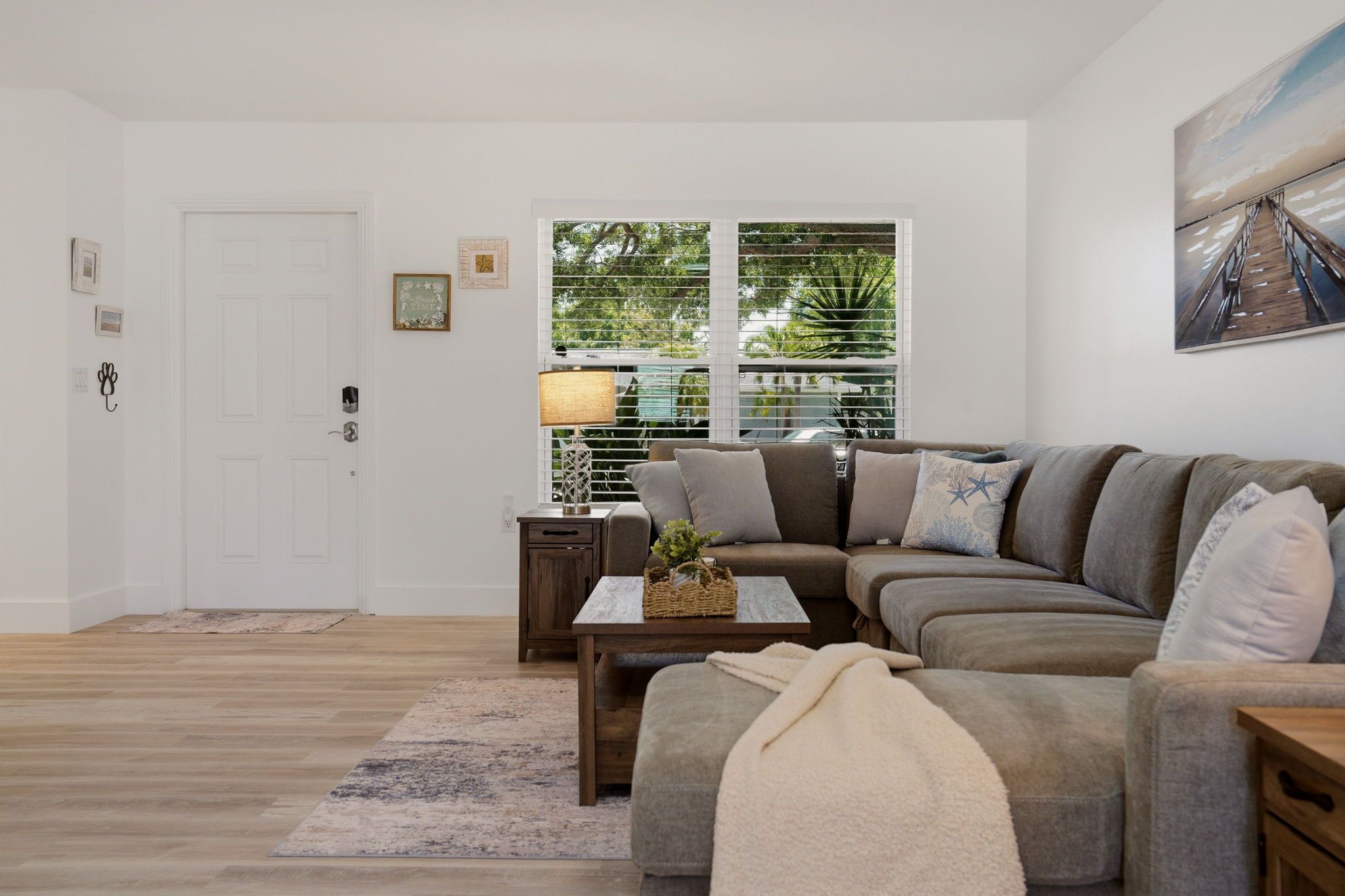 Una sala de estar con un sofá modular, una mesa de centro, una lámpara y vistas al exterior por una ventana.