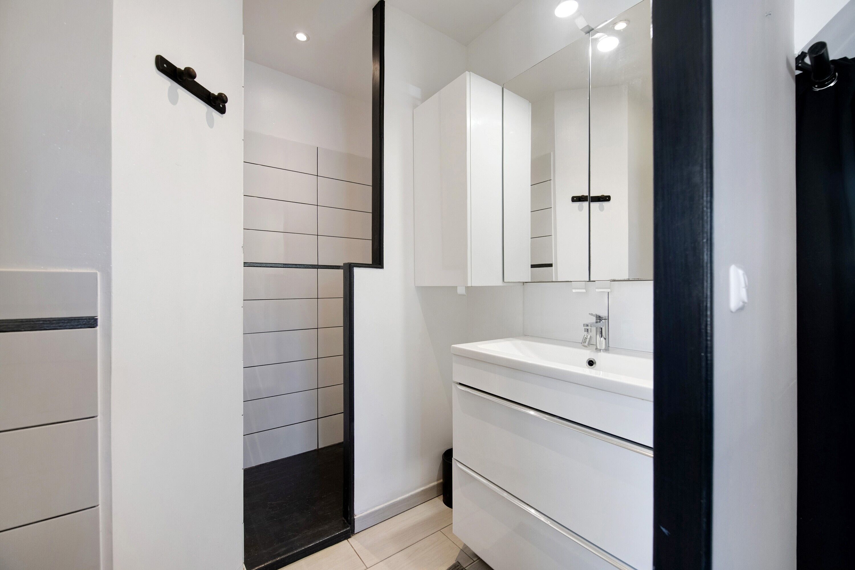 Een moderne badkamer met een douche, een wastafel en een spiegel.