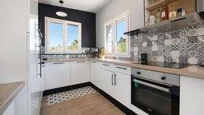 Una cocina moderna con armarios blancos, un salpicadero negro y un horno empotrado.