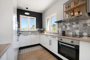 A modern kitchen with white cabinets, a black backsplash, and a built-in oven.