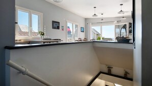 Una cocina moderna con zona de comedor, ventanas amplias y una escalera.