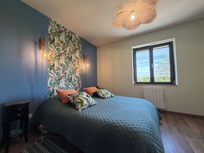Ein Schlafzimmer mit Bett, Fenster, Wand mit Blumenmuster und Deckenleuchte.