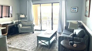Ein Wohnzimmer mit Sofa, Sessel, Couchtisch und Fernseher.